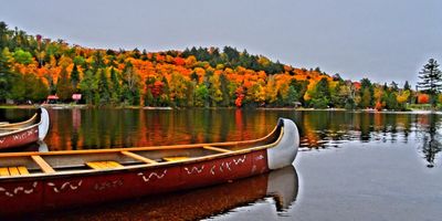 Fall view of a dock on a Muskoka lake with calm water and autumn trees along the shoreline”