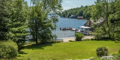 cottage shoreline with boathouse and green grass